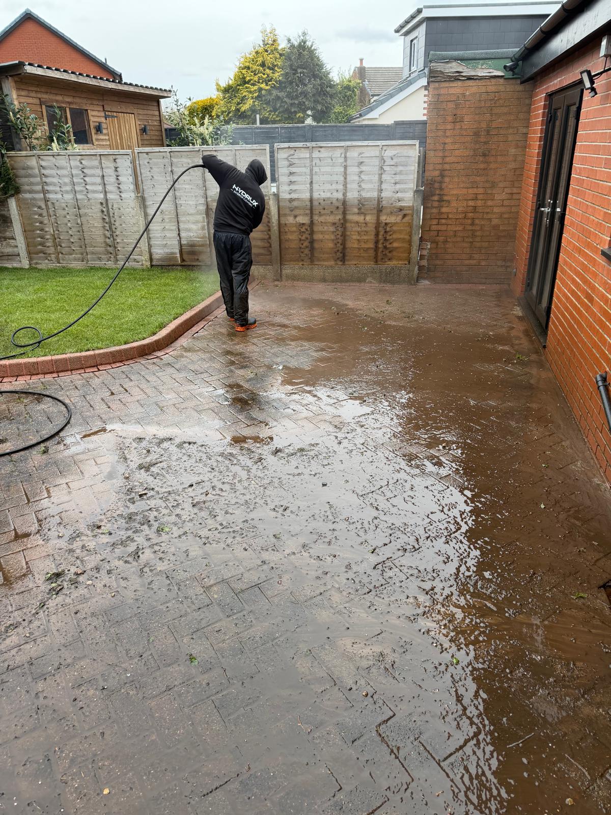 Rear block paved patio being pressure washed